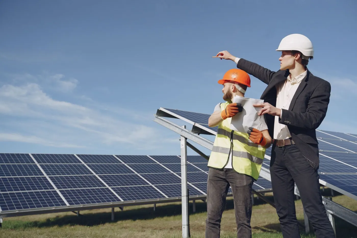 A client and a site engineer reviewing plans beside a solar array